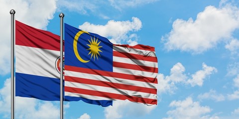Paraguay and Malaysia flag waving in the wind against white cloudy blue sky together. Diplomacy concept, international relations.
