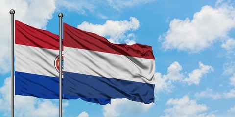 Paraguay and Netherlands flag waving in the wind against white cloudy blue sky together. Diplomacy concept, international relations.