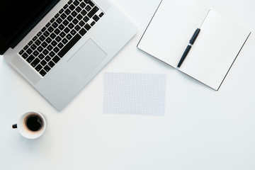 Top view of office table. White office desk table with laptop, cup of coffee and supplies.