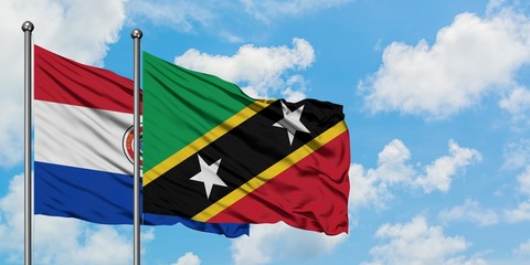 Paraguay and Saint Kitts And Nevis flag waving in the wind against white cloudy blue sky together. Diplomacy concept, international relations.