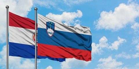 Paraguay and Slovenia flag waving in the wind against white cloudy blue sky together. Diplomacy concept, international relations.