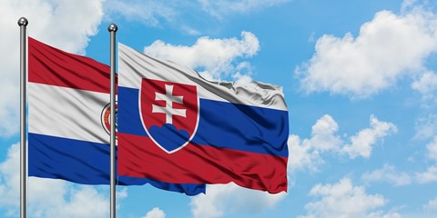 Paraguay and Slovakia flag waving in the wind against white cloudy blue sky together. Diplomacy...