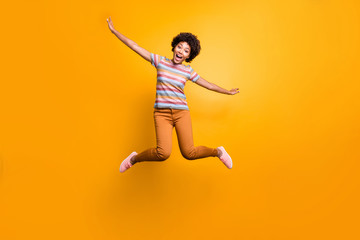 Fototapeta na wymiar Full length body size photo of cheerful pretty girlish youngster with hands like spreading wings orange trousers striped t-shirt curly wavy isolated vivid color background