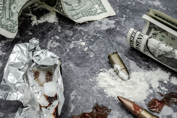 Mock-up concept of illegal drug dealing on a work surface. Showing dollar bills, mock-up bullets together with prop blood together with smoking foil. - obrazy, fototapety, plakaty