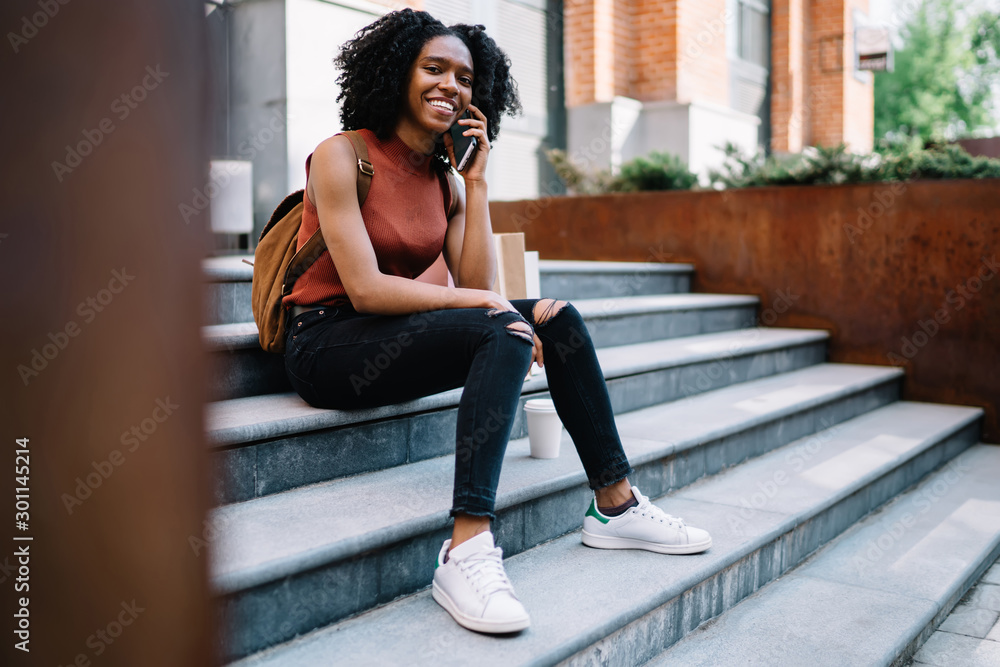 Poster portrait of cheerful female student dressed in casual apparel smiling at camera while communicating 