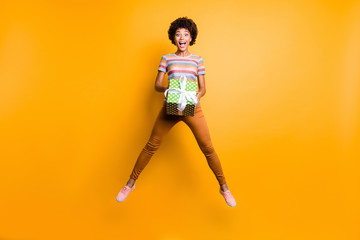 Full length body size photo of cheerful positive cute nice charming fascinating curly wavy girlfriend wearing striped t-shirt orange pants trousers footwear isolated over vivid yellow color background