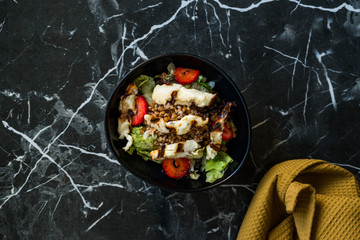 Grilled Halloumi Cheese Salad with Strawberry Slices and Buckwheat / Hellim in Black Bowl on Dark Granite Surface.