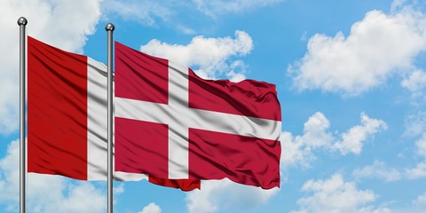 Peru and Denmark flag waving in the wind against white cloudy blue sky together. Diplomacy concept, international relations.