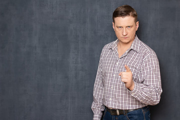 Portrait of serious concentrated man raising index finger