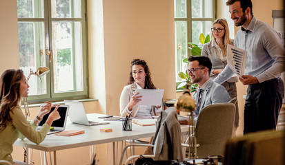 Group of young business people working together while sitting at the office desk.	