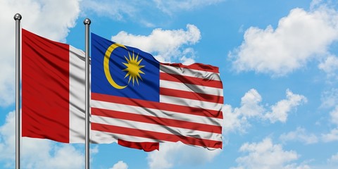 Peru and Malaysia flag waving in the wind against white cloudy blue sky together. Diplomacy concept, international relations.