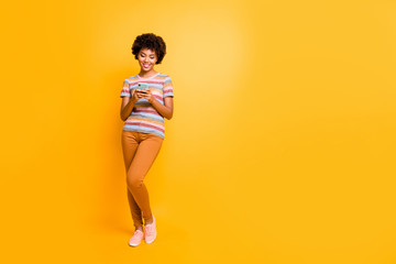 Full length photo of positive cheerful afro american girl stand use smartphone type sms her friend...