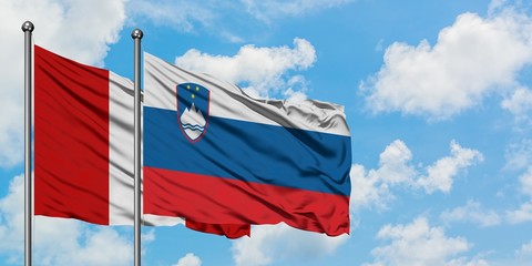 Peru and Slovenia flag waving in the wind against white cloudy blue sky together. Diplomacy concept, international relations.