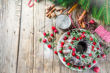 Homemade Christmas baking. Dark chocolate gingerbread christmas bundt cake with powdered sugar, fresh cranberries and rosemary, with xmas tree decoration