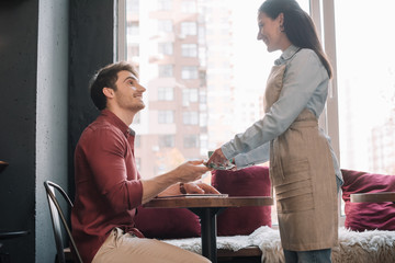 smiling waitress serving coffee to man with laptop