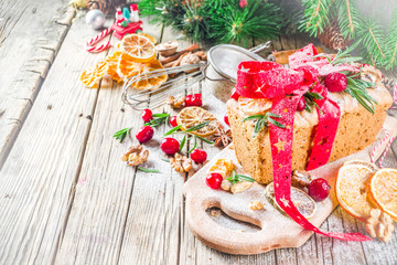 Obraz na płótnie Canvas Traditional Christmas and winter holidays baking. Fruit cake with icing, nuts, berry dry orange and rosemary. Sweet homebaked cake on old wooden background with Christmas decoration