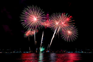 Amazing beautiful colorful fireworks display on celebration night, showing on the sea beach with multi color of reflection on water