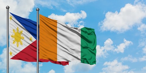 Philippines and Cote D'Ivoire flag waving in the wind against white cloudy blue sky together. Diplomacy concept, international relations.