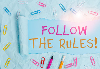 Conceptual hand writing showing Follow The Rules. Concept meaning go with regulations governing conduct or procedure Stationary and torn cardboard on a plain pastel table backdrop