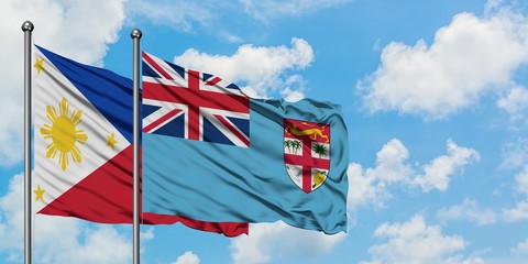 Philippines and Fiji flag waving in the wind against white cloudy blue sky together. Diplomacy concept, international relations.