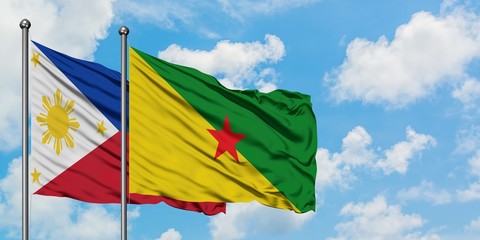 Philippines and French Guiana flag waving in the wind against white cloudy blue sky together. Diplomacy concept, international relations.