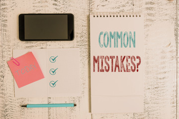 Writing note showing Common Mistakes Question. Business concept for repeat act or judgement misguided making something wrong Square spiral notebook marker smartphone sticky note on wood background