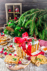 Traditional Christmas and winter holidays baking. Fruit cake with icing, nuts, berry dry orange and rosemary. Sweet homebaked cake on old wooden background with Christmas decoration