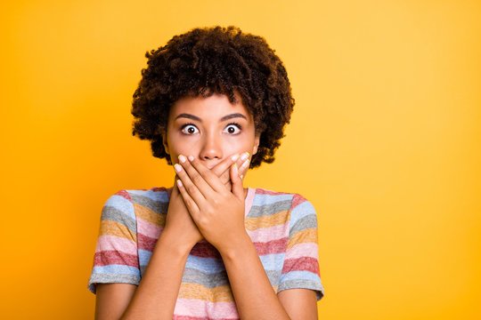 Closeup photo of beautiful dark skin lady looking eyes full fear calm herself hiding mouth wear casual stylish striped t-shirt isolated yellow background