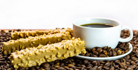 a cup of coffee with cookies, coffee grains scattered on a table near a cup with a coffee