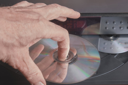 male hand take out blue ray disc from player in home theater