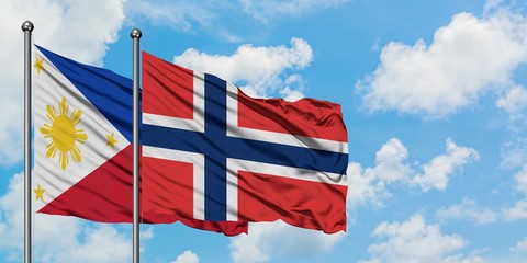 Philippines and Norway flag waving in the wind against white cloudy blue sky together. Diplomacy...