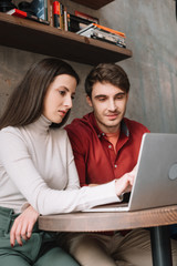 young couple working together on laptop in coffee shop
