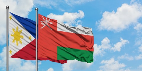 Philippines and Oman flag waving in the wind against white cloudy blue sky together. Diplomacy concept, international relations.
