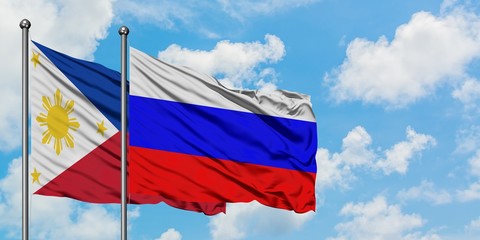 Philippines and Russia flag waving in the wind against white cloudy blue sky together. Diplomacy...