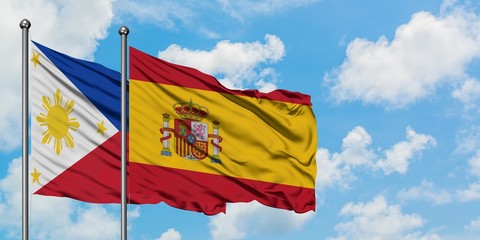 Philippines and Spain flag waving in the wind against white cloudy blue sky together. Diplomacy concept, international relations.