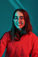 Sincere smile. Studio shot indoors with neon light. Portrait of beautiful young girl