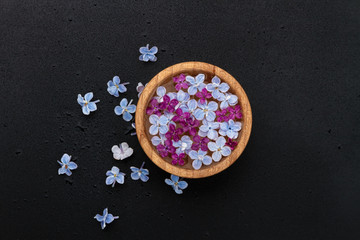 Obraz na płótnie Canvas Floating lilac flowers in a bamboo bowl