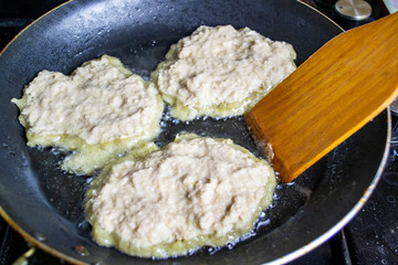 potato pancakes are fried in a pan, boiling oil