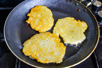 potato pancakes are fried in a pan, boiling oil