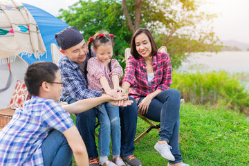 asian family travel and camping in forest, they sitting and feel happy at lakeside , they use hand touch hand together, hand in hand, family activity, adventure and travel