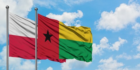Poland and Guinea Bissau flag waving in the wind against white cloudy blue sky together. Diplomacy...
