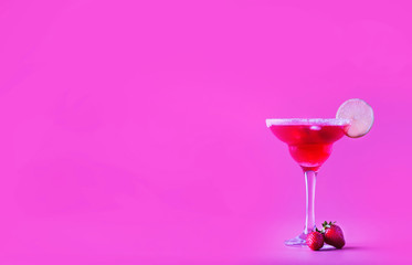 Strawberry red margarita alcoholic cocktail with tequila, liqueur, berries, lime juice, sugar and ice, pink background, copy space