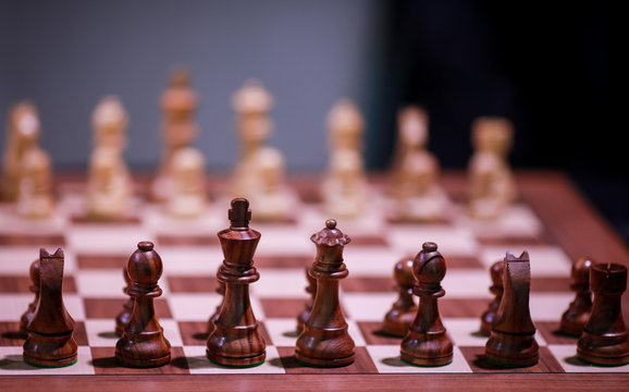 Shallow depth of field (selective focus) image with wooden chess pieces on a wooden table before a professional competition.