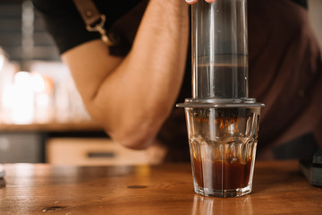 partial view of barista preparing coffee with aeropress