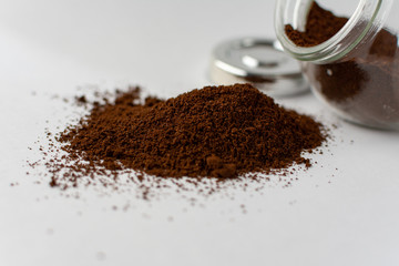 Glass jar with ground coffee upside down. Rashes ground coffee from a jar on a white background.
