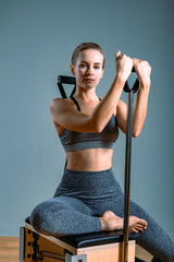 Palates trainer girl posing for a reformer in the gym. Fitness concept, special fitness equipment, healthy lifestyle, plastic. Copy space, sport banner for advertising.