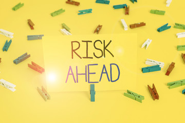 Text sign showing Risk Ahead. Business photo text A probability or threat of damage, injury, liability, loss Colored clothespin papers empty reminder yellow floor background office