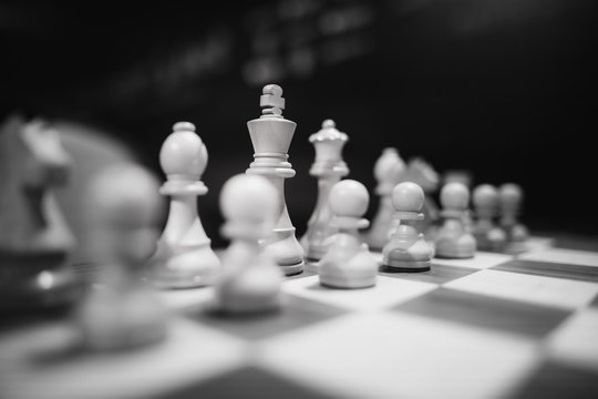 Monochrome shallow depth of field (selective focus) image with wooden chess pieces on a wooden table before a professional competition.