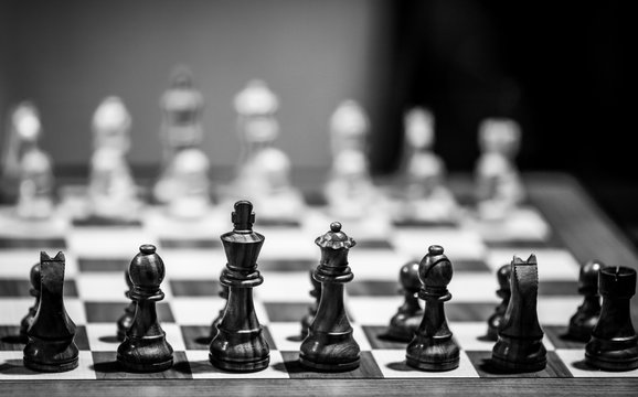 Monochrome shallow depth of field (selective focus) image with wooden chess pieces on a wooden table before a professional competition.