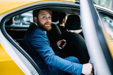 Portrait of Caucasian male banker in formal wear looking at camera during business trip in taxi...